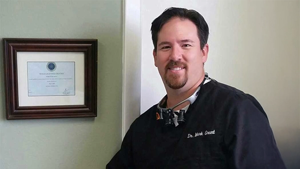 Dentist Mark Grant In Front Of Diploma