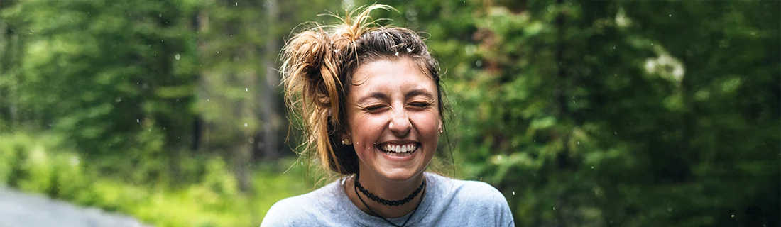 Woman Smiling Among Trees And Shubbery